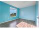 Bedroom featuring blue walls, wood-look flooring, and a bright window overlooking greenery at 638 Kangaroo Dr, Poinciana, FL 34759