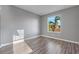 A gray bedroom featuring a view of palm trees through the window and wood-look flooring at 638 Kangaroo Dr, Poinciana, FL 34759