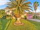 Two-story home with manicured lawn, mature landscaping, and pink garage door at 638 Kangaroo Dr, Poinciana, FL 34759