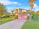 Two-story home with manicured lawn, mature landscaping, and pink garage door at 638 Kangaroo Dr, Poinciana, FL 34759