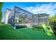 Backyard with well-manicured lawn, trampoline with slide, and screened-in lanai at 6953 Broglie St, Orlando, FL 32827