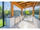 Outdoor kitchen features stainless steel appliances, ceiling fan, and stone countertops at 6953 Broglie St, Orlando, FL 32827
