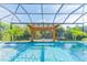 An enclosed pool with a jacuzzi and a seating area under a wooden pergola at 6953 Broglie St, Orlando, FL 32827