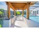 Poolside kitchen and bar area under a wooden pergola with built-in grill and cabinets at 6953 Broglie St, Orlando, FL 32827