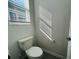 Powder room with toilet, window with blinds, and gray tile flooring at 8023 Sayings Dr, Winter Garden, FL 34787