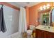 Clean bathroom with a shower-tub, orange walls, and a dark wood vanity with integrated sink at 8374 Quimby Cir # 8374, Davenport, FL 33896