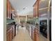 Long, galley-style kitchen boasts stainless appliances, granite counters, and wood cabinets at 8374 Quimby Cir # 8374, Davenport, FL 33896