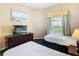 Well-lit bedroom has two beds, TV, dresser, and a tranquil ambiance at 8774 Worldquest Blvd # 7503, Orlando, FL 32821
