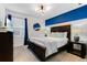 Comfortable bedroom featuring large bed frame, blue accent wall, and modern lighting at 8943 Amelia Downs Trl, Kissimmee, FL 34747