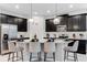 Modern kitchen featuring a spacious island with seating, sleek black cabinets, and stainless steel appliances at 8943 Amelia Downs Trl, Kissimmee, FL 34747