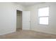 An unfurnished bedroom includes neutral carpets, an open closet, and a large window at 9016 Pyrus St, Kissimmee, FL 34747