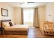Bright bedroom featuring hardwood floors, a large window, and a crib at 9016 Pyrus St, Kissimmee, FL 34747