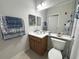 Well-lit bathroom features a vanity with wood cabinets and a decorative blue and white shower curtain at 9435 Myrtle Creek Ln # 304, Orlando, FL 32832