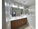 Dual sink bathroom with a large framed mirror and wood cabinets providing ample counter space at 9435 Myrtle Creek Ln # 304, Orlando, FL 32832