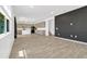 Open concept living and kitchen area with continuous wood laminate flooring and a dark accent wall at 1003 Sugarwood St, Davenport, FL 33837