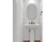 This powder room features a sleek pedestal sink, an oval mirror, and modern fixtures at 1003 Sugarwood St, Davenport, FL 33837