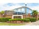Landscaped entrance to Sand Point community, featuring brick sign and a glimpse of homes and community pool at 1190 Sandestin Way, Orlando, FL 32824