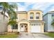 Charming yellow two-story home with a well-manicured lawn and a welcoming front porch, accented by a palm tree at 1190 Sandestin Way, Orlando, FL 32824