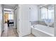 Bright bathroom with a white tub, tiled walls, and natural light from the window at 199 Maple Dr, Kissimmee, FL 34759