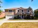 Two-story home with tan siding, attached two car garage, manicured lawn, and well-maintained landscaping at 1930 Knollcrest Dr, Clermont, FL 34711
