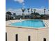 Community pool surrounded by lounge chairs and palm trees on a sunny day at 2130 Cascades Blvd # 108, Kissimmee, FL 34741