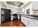 Galley-style kitchen featuring black appliances, wood floors, and white cabinetry at 2430 Mill Run Blvd, Kissimmee, FL 34744
