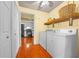 Laundry room features wood floors, washer, dryer, storage shelf, and bright yellow walls at 2430 Mill Run Blvd, Kissimmee, FL 34744