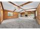 Bright living room with wood-paneled walls, ceiling beams, and gray carpet flooring at 2430 Mill Run Blvd, Kissimmee, FL 34744