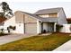 Front exterior of home with a two-car garage, lush green lawn, and a beautifully paved driveway at 2615 Autumn Green Dr, Orlando, FL 32822