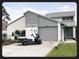 Charming two-story home featuring a well-manicured lawn, gray siding, an attached garage, and a personal golf cart at 2615 Autumn Green Dr, Orlando, FL 32822