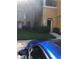 View of the condo building with tan exterior and well-maintained landscaping and a blue car in the foreground at 3567 Conroy Rd # 1213, Orlando, FL 32839
