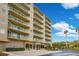 Exterior facade view of a condo building with balconies, lush landscaping, and a blue sky backdrop at 4 Oceans West Blvd # 301B, Daytona Beach Shores, FL 32118