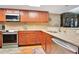 Kitchen featuring wood cabinets, granite counters, tile backsplash, and updated stainless steel appliances at 4 Oceans West Blvd # 301B, Daytona Beach Shores, FL 32118