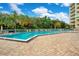 A rectangular pool is surrounded by green trees, and a building with balconies at 4 Oceans West Blvd # 301B, Daytona Beach Shores, FL 32118