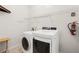 Well-lit laundry room featuring modern washer and dryer with overhead shelving and an extinguisher at 5365 Dahlia Reserve Dr, Kissimmee, FL 34758