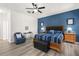 Spacious bedroom with king bed, blue accent wall, and gray wood-look flooring at 5365 Dahlia Reserve Dr, Kissimmee, FL 34758
