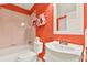 Bright bathroom featuring a white tub and sink set against a vibrant orange wall, creating a lively and clean aesthetic at 541 Campus St, Celebration, FL 34747