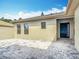 Home exterior featuring a dark front door, neutral siding, and paved patio against a blue, partially cloudy sky at 567 Villa Park Rd, Kissimmee, FL 34759
