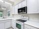 Kitchen features white appliances, quartz countertops, overhead microwave, and stainless steel sink at 567 Villa Park Rd, Kissimmee, FL 34759