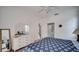 Bright bedroom features a stylish blue patterned bedspread, modern ceiling fan, and a white dresser with a large mirror at 624 Montana Ave, Davenport, FL 33897