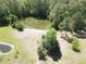 Aerial view of the home's pond surrounded by a grassy field with mature trees, showcasing a tranquil outdoor space at 624 Montana Ave, Davenport, FL 33897