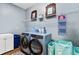 Light and airy laundry room with blue washer and dryer, and shelving for organization at 6886 Sundrop St, Harmony, FL 34773
