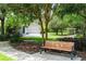 Lovely view of a bench in a green neighborhood, with mature trees and a charming home in the background at 6886 Sundrop St, Harmony, FL 34773