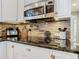 Kitchen detail with microwave, brick backsplash, knife block, and black countertops at 715 Honeysuckle Ave, Celebration, FL 34747