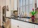 Kitchen detail featuring stainless steel appliances, white cabinetry, black countertops, and brick backsplash at 715 Honeysuckle Ave, Celebration, FL 34747