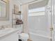 Bright bathroom with a tub and shower, toilet, vanity, shelving unit, and large window at 7830 Myrtle Oak Ln, Kissimmee, FL 34747