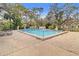 Community pool with lounge chairs, surrounded by mature trees and landscaping at 7830 Myrtle Oak Ln, Kissimmee, FL 34747