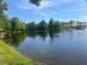 Picturesque lake view featuring mature trees, blue umbrellas and a water fountain, offering a serene outdoor setting at 8369 Riverdale Ln # 1, Davenport, FL 33896