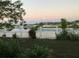 Picturesque backyard with a white picket fence overlooking a serene pond at sunset at 954 Hacienda Cir, Kissimmee, FL 34741