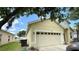 Side view of the home featuring a two-car garage, well-kept lawn, and partial driveway view at 954 Hacienda Cir, Kissimmee, FL 34741
